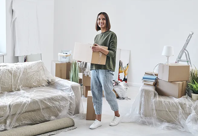 CBM Smart Services professional cleaners smiling in a bright, prepared empty room with boxes, ready to perform a stress-free move-in or move-out cleaning service in Massachusetts.