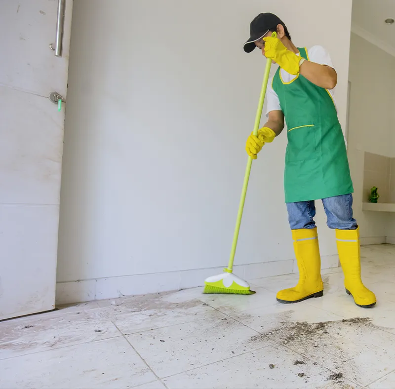 CBM Smart Services professional sweeping heavy construction dust and debris from a tiled floor with a broom, illustrating post-construction cleaning in Massachusetts.